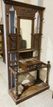 A large oak hall stand with carved detailing, single drawer and wooden coat pegs