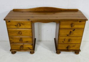 A modern pine kneehole desk with eight drawers