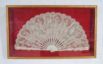 A framed antique fan with bone sticks and lace decoration