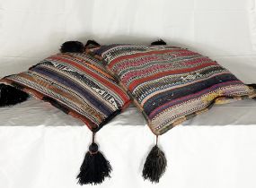 A pair of large woven woollen cushions, possibly North African, with tassels to each corner