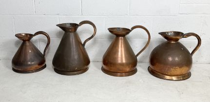 A collection of four large antique copper jugs