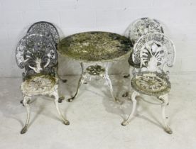 A weathered metal circular garden table with four matching chairs