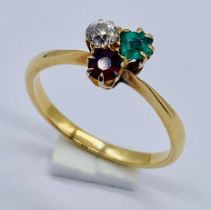 An unmarked 9ct gold three stone ring set with a diamond, emerald and a ruby