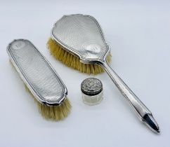 Two hallmarked silver dressing table brushes along with a small silver lidded pot