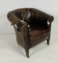 A distressed leather tub chair on castors with studded detailing