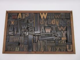 A printers style tray containing a collection of vintage letterpress wooden printing blocks