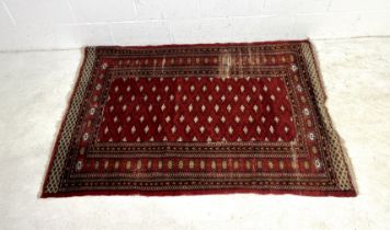 An Eastern red ground rug, with worn patches. 128cm x 178cm