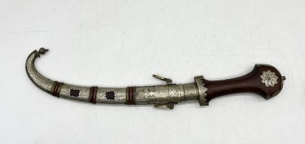 An Eastern Jambiya dagger with wooden grip and ornate scabbard