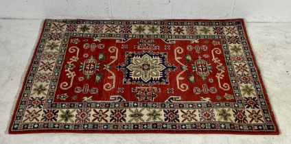 A red ground rug. 102cm x 150cm
