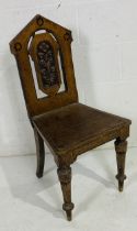 A gothic oak hall chair with carved decoration.