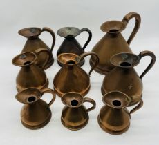 A collection of nine various sized copper jugs - largest half gallon