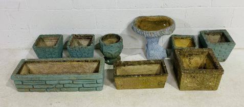 A collection of various concrete garden pots and troughs, some painted blue, along with a painted