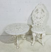 A white painted cast iron low circular garden table, along with a cast iron garden chair