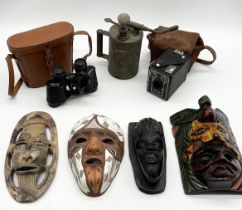 A collection of items including various masks, Brownie camera, oil can etc.