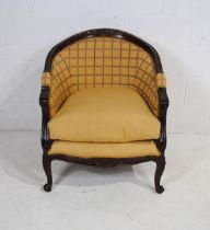 A reproduction upholstered tub chair, with carved detailing