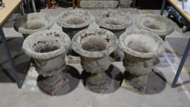 Seven weathered reconstituted stone garden urns on plinths - diameter 41cm, height 54cm