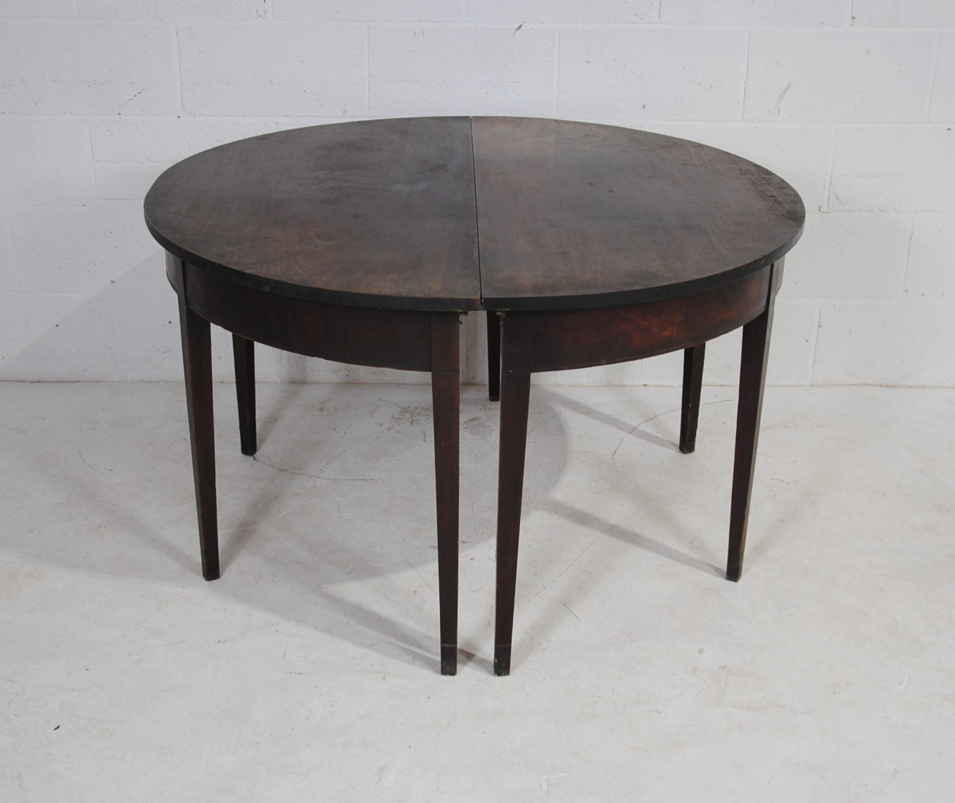 A pair of Georgian mahogany demi lune tables, raised on tapering legs
