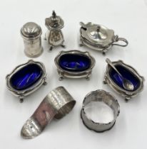 A collection of hallmarked silver salts, serviette rings, mustard etc.