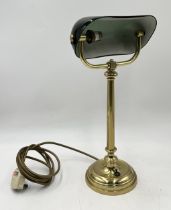 A brass bankers lamp with green glass shade