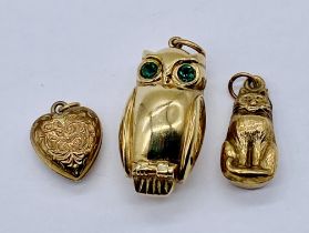 A 9ct gold charm in the form of an owl along with a cat charm and a heart shaped locket, total