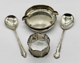 A silver weighted ashtray along with two silver spoons and a serviette ring
