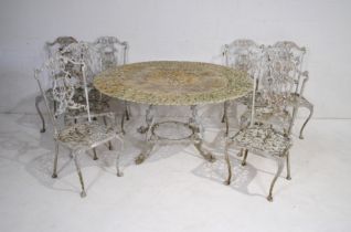 A weathered cast aluminium circular garden table with a set of eight chairs, with lyre backs - one