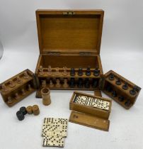 A turn of the century oak part games compendium with boxwood and ebony chess set, two part domino