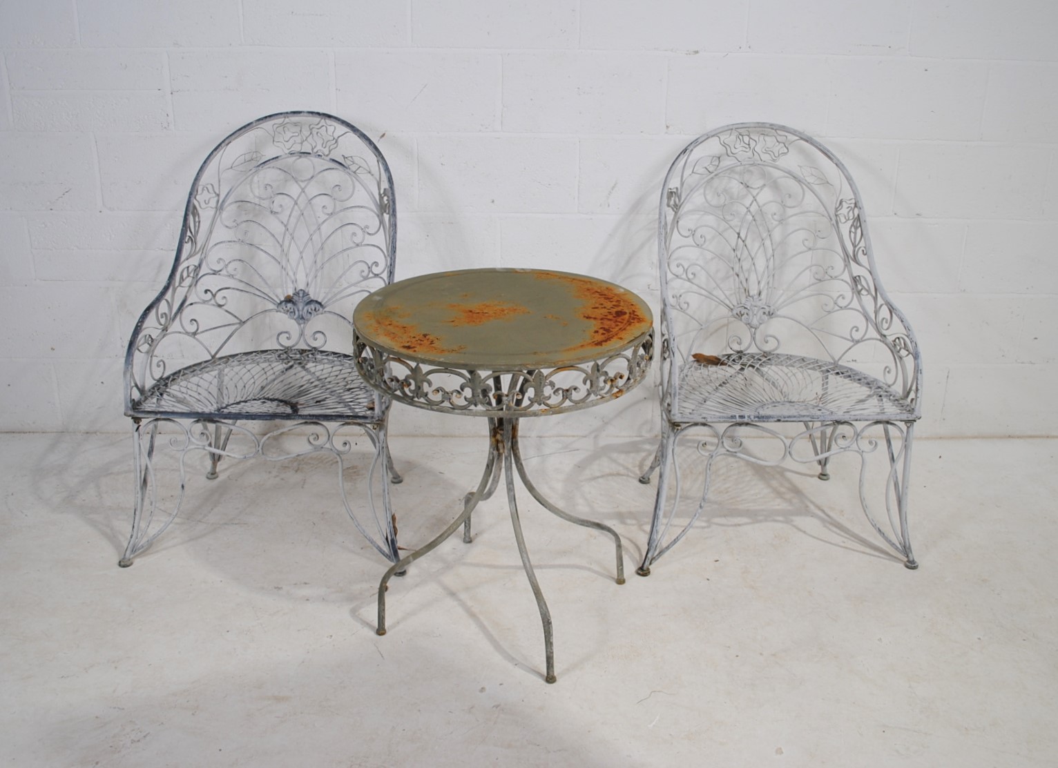 A weathered metal garden bistro table with two chairs