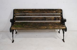 A well weathered cast iron garden bench with, wooden slatted seat