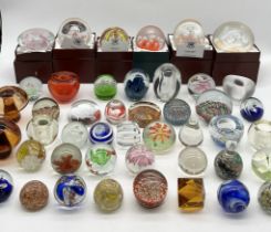 A large collection of glass paperweights including a number of larger boxed examples