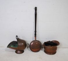 Two copper coal scuttles along with a copper warming pan