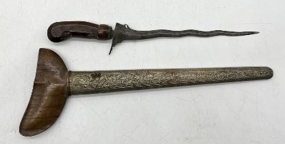 An Eastern Kris dagger with carved wooden handle, ornate blade and decorated scabbard