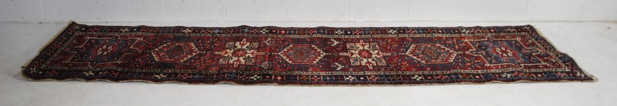 A hand-woven red ground Eastern runner - 347cm x 85cm