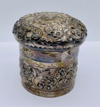 A hallmarked silver lidded dressing table pot with repousse decoration, weight 126.7g