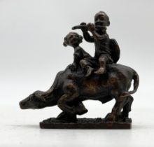 A well cast small bronze Eastern figure group of children riding a water buffalo, height 5.75cm