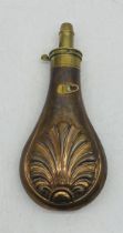 A vintage copper powder flask with embossed detailing