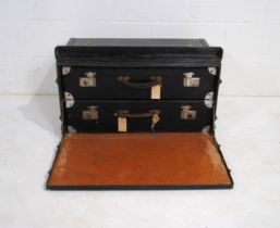 A vintage black travel trunk, with drop-down front to reveal two suitcases - length 77cm