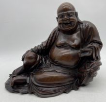 A large vintage carved figure of Buddha with bone teeth and holding a bat, approx. 37cm width