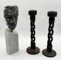 A plaster sculpture of a face on marble base along with pair of wooden barley twist candlesticks