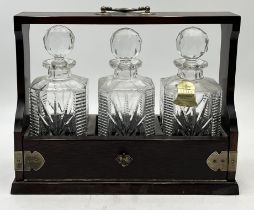 A wooden cased, brass bound tantalus with three cut glass decanters