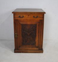 A turn of the century oak cupboard, with carved detailing depicting stylised dolphins beneath a