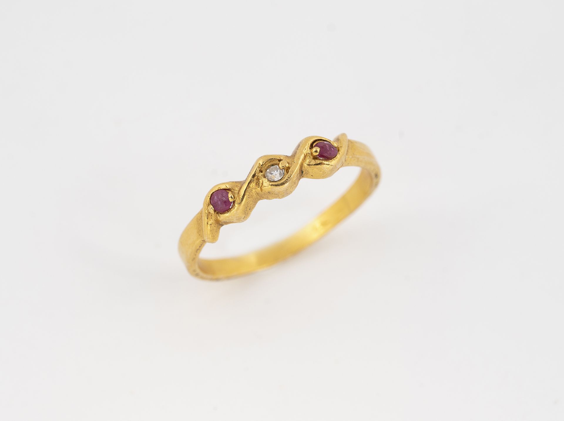 Gold metal ring decorated with two red stones and a white stone.Fingers: 57.