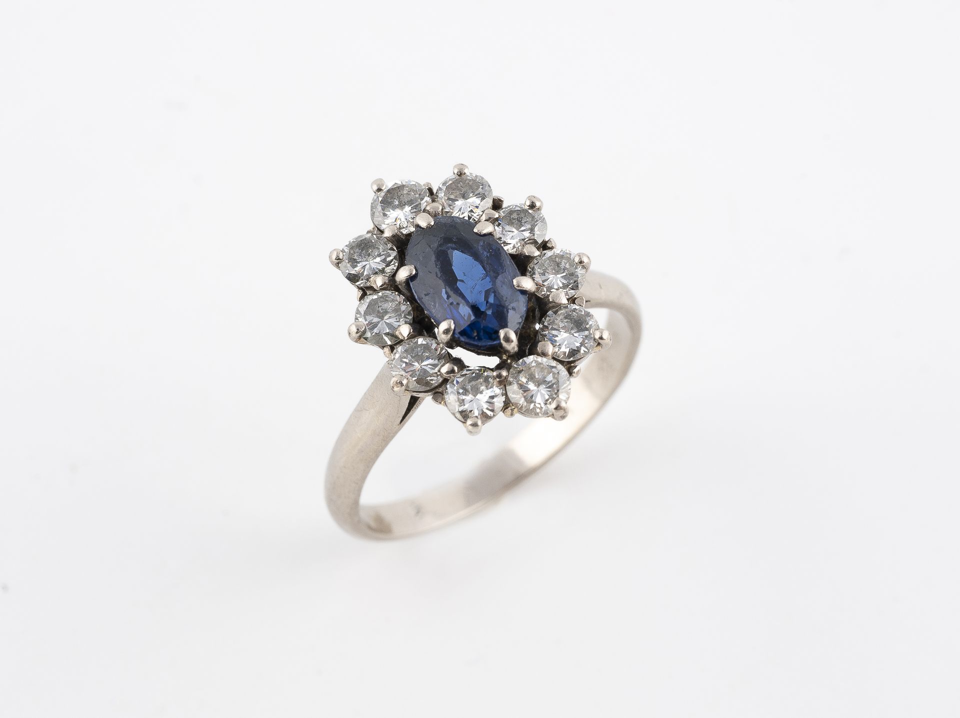 18k gray gold ring (750 thousandths), decorated with a blue faceted stone in a surrounding diamonds 