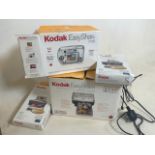 A Kodak easy share printer dock, camera and photos paper.