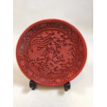 An oriental cinnabar style lacquer carved plate detailing a dragon and foliage W:20cm