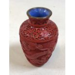 An oriental Cinnabar style lacquerware vase carved with dragon and foliage with blue enamel base and