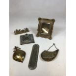 An ornate brass mirror, a brass inkwell with glass, a decorative finger plate, a brass pouch and
