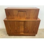 A Mid century veneered drinks cabinet with door to slide out mirrored bar above storage cupboard. (