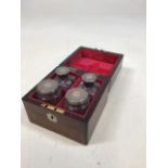 An oak velvet lined travel box with silver topped cut glass bottles in fitted compartments. Inset