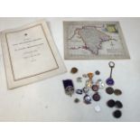 A vintage map of Devon with regimental brass buttons, military badges and other items